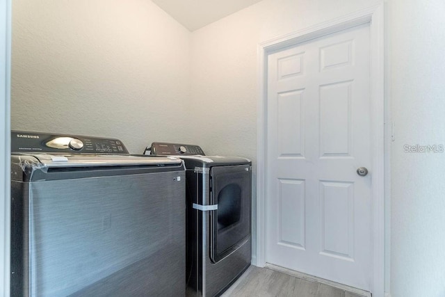 laundry area featuring separate washer and dryer and light hardwood / wood-style flooring