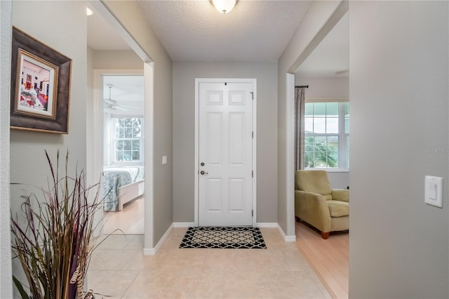 foyer with ceiling fan, light tile patterned floors, and a textured ceiling