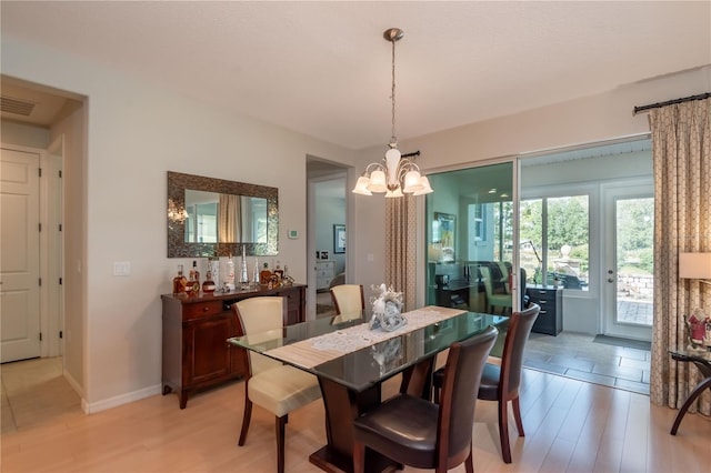 dining space featuring light wood-type flooring and an inviting chandelier