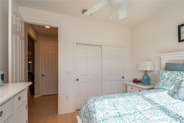 bedroom with light hardwood / wood-style flooring, ceiling fan, and a closet