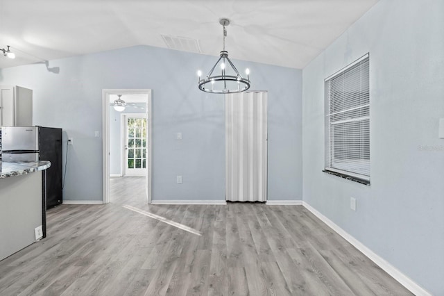 unfurnished dining area featuring ceiling fan with notable chandelier, lofted ceiling, and light wood-type flooring