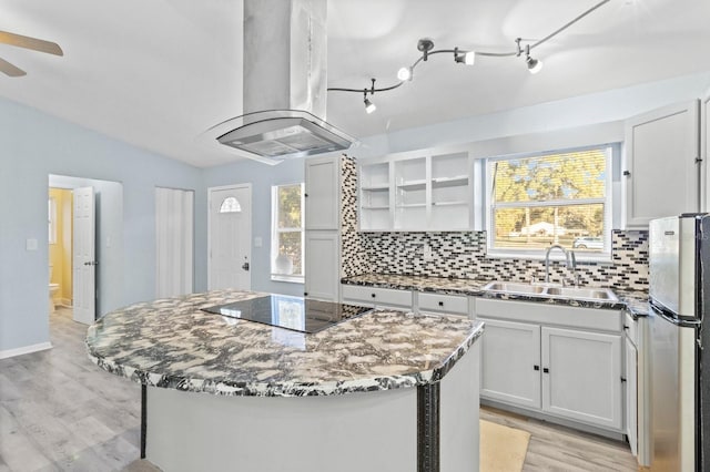 kitchen featuring stainless steel fridge, island range hood, black electric cooktop, and a kitchen island