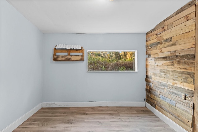 unfurnished room with wood walls and light hardwood / wood-style floors