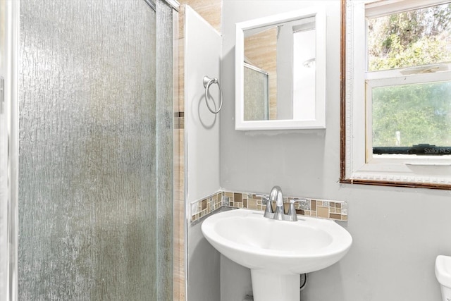 bathroom with tasteful backsplash, toilet, a shower with shower door, and sink