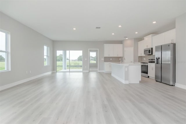 kitchen featuring a center island with sink, a wealth of natural light, white cabinets, and appliances with stainless steel finishes