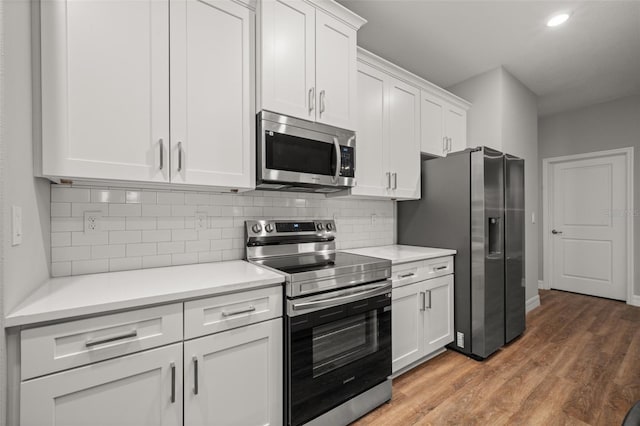 kitchen with appliances with stainless steel finishes, white cabinets, backsplash, and dark hardwood / wood-style floors