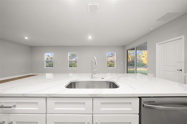 kitchen featuring sink, stainless steel dishwasher, white cabinets, and light stone counters