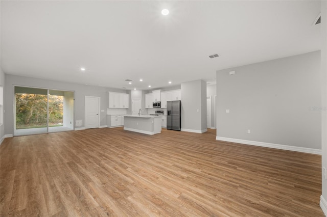 unfurnished living room with light hardwood / wood-style floors and sink