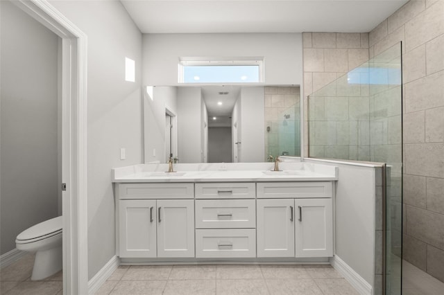 bathroom featuring tile patterned floors, a tile shower, vanity, and toilet