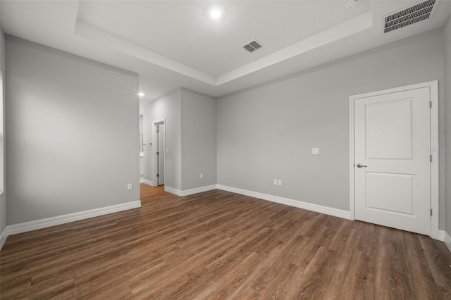 empty room with dark wood-type flooring and a raised ceiling