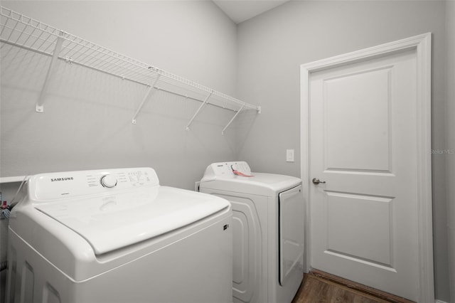 clothes washing area with dark hardwood / wood-style flooring and washing machine and clothes dryer