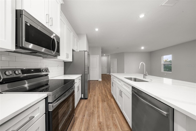 kitchen with light hardwood / wood-style flooring, stainless steel appliances, white cabinets, and sink