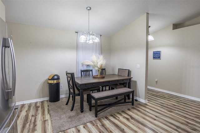 dining room featuring an inviting chandelier, vaulted ceiling, and hardwood / wood-style flooring