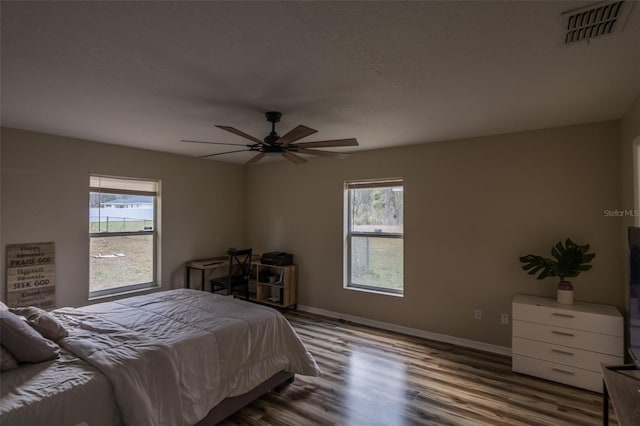 bedroom featuring multiple windows, ceiling fan, and hardwood / wood-style flooring