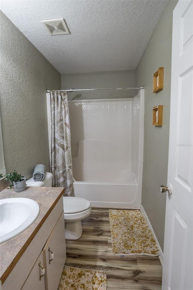 full bathroom featuring vanity, a textured ceiling, hardwood / wood-style flooring, and toilet