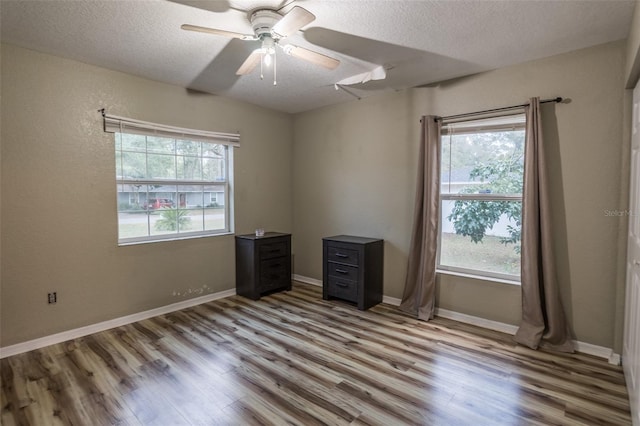 empty room with ceiling fan, light hardwood / wood-style floors, and a textured ceiling