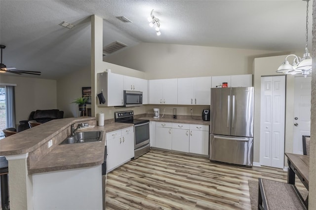 kitchen featuring kitchen peninsula, white cabinetry, stainless steel appliances, and decorative light fixtures