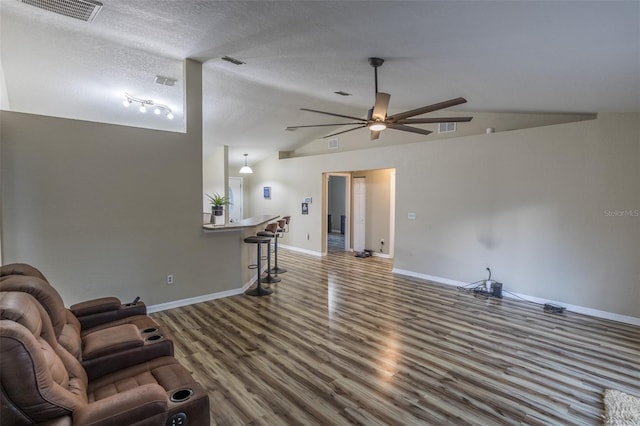 living room with hardwood / wood-style floors, ceiling fan, a textured ceiling, and vaulted ceiling