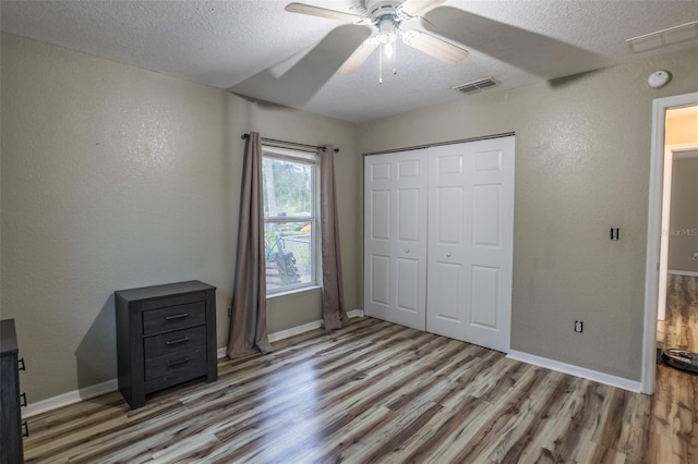 unfurnished bedroom featuring a textured ceiling, light wood-type flooring, a closet, and ceiling fan