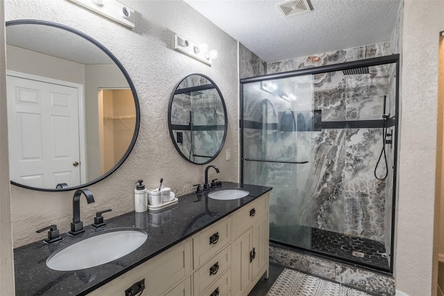 bathroom with a shower with door, vanity, and a textured ceiling