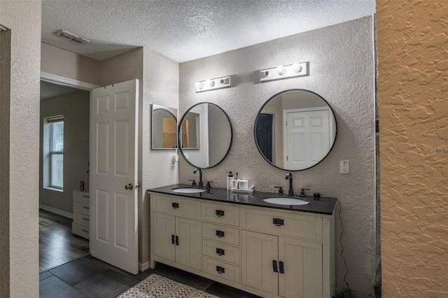 bathroom featuring tile patterned flooring, vanity, and a textured ceiling