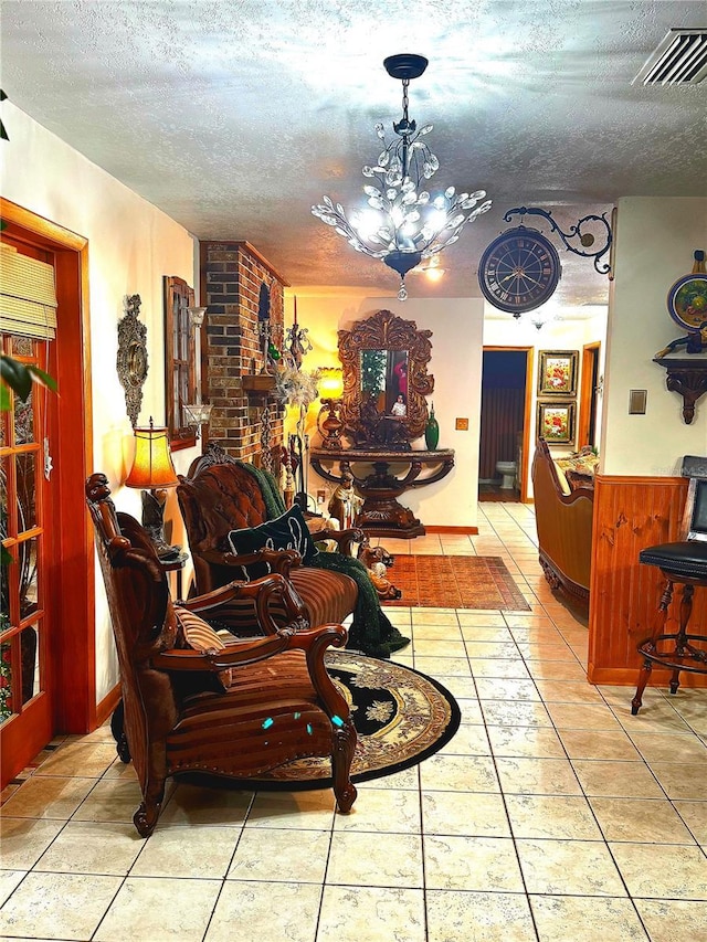 living room with wood walls, light tile patterned floors, a chandelier, and a textured ceiling