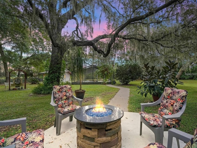 patio terrace at dusk featuring a yard and a fire pit