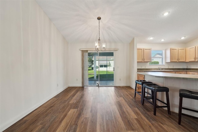 kitchen with vaulted ceiling, dark hardwood / wood-style floors, hanging light fixtures, a notable chandelier, and light brown cabinets