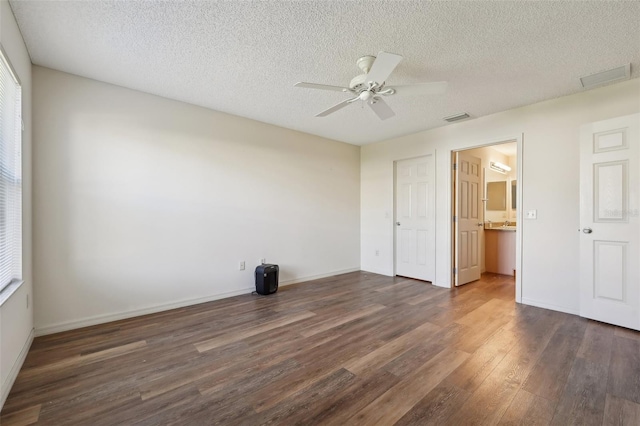 unfurnished bedroom with ceiling fan, dark hardwood / wood-style flooring, ensuite bath, and a textured ceiling