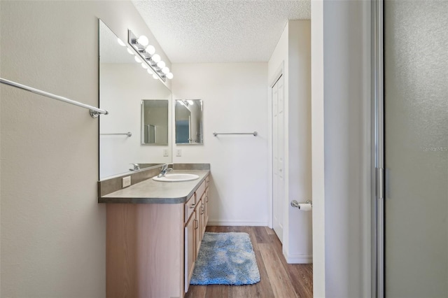 bathroom with wood-type flooring, a textured ceiling, and vanity