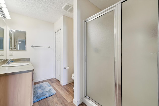 bathroom with vanity, wood-type flooring, a textured ceiling, and walk in shower