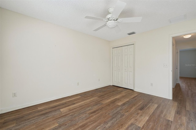 unfurnished bedroom with dark wood-type flooring, ceiling fan, a closet, and a textured ceiling