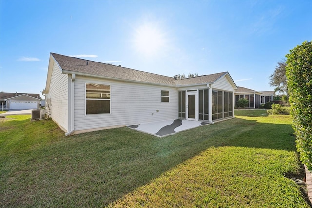 rear view of house featuring a patio, a sunroom, central AC, and a lawn