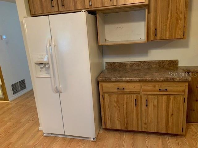 kitchen with white refrigerator with ice dispenser and light wood-type flooring