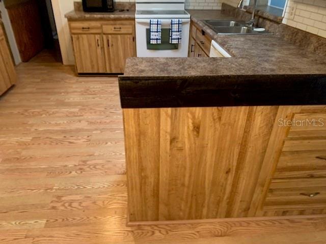 kitchen with stove, kitchen peninsula, sink, and tasteful backsplash