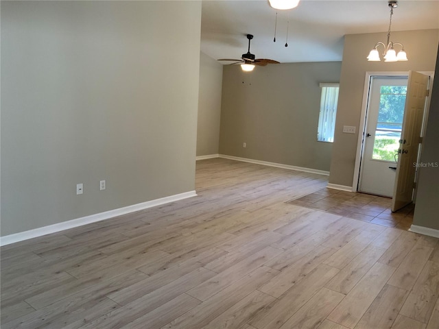 interior space with ceiling fan with notable chandelier and light hardwood / wood-style flooring