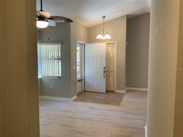 foyer featuring ceiling fan with notable chandelier, light wood-type flooring, and vaulted ceiling