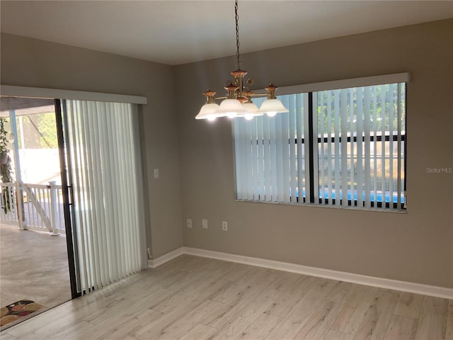 spare room featuring light hardwood / wood-style flooring and a chandelier