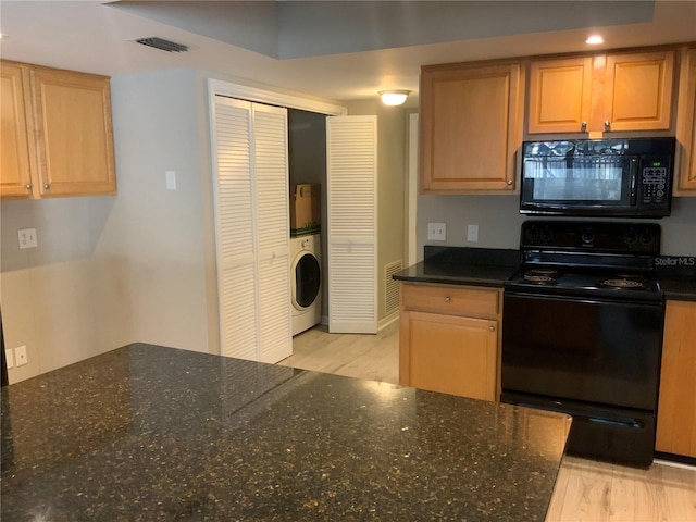 kitchen featuring black appliances, washer / dryer, and dark stone counters