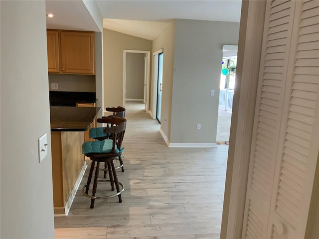 hall featuring light hardwood / wood-style floors and lofted ceiling