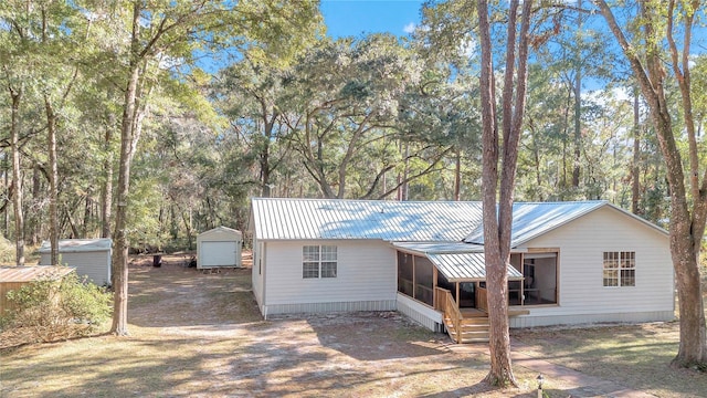 view of front of house with a storage shed and a sunroom