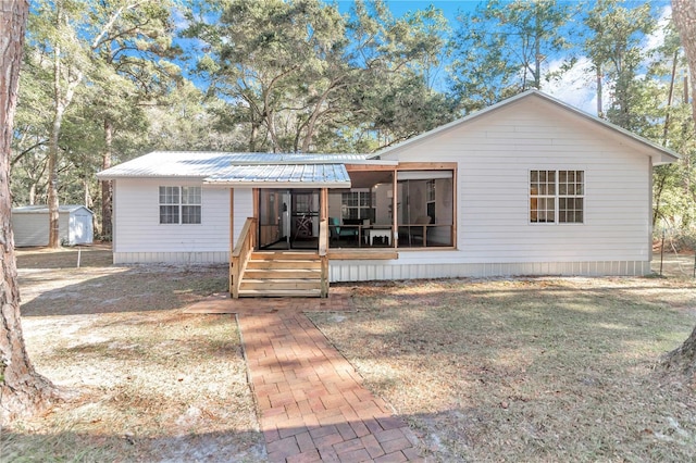 view of front of house featuring a sunroom, a front lawn, and a storage unit