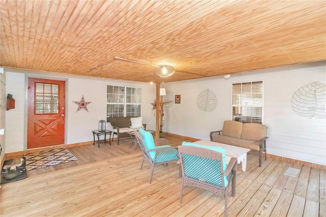 living area with light wood-type flooring, wooden ceiling, and wood walls