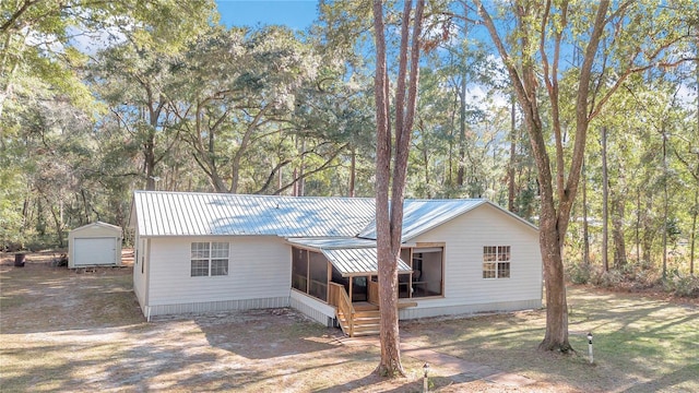 view of front of property featuring a sunroom and a shed