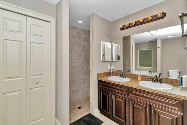 bathroom with tile patterned flooring, a tile shower, vanity, and toilet