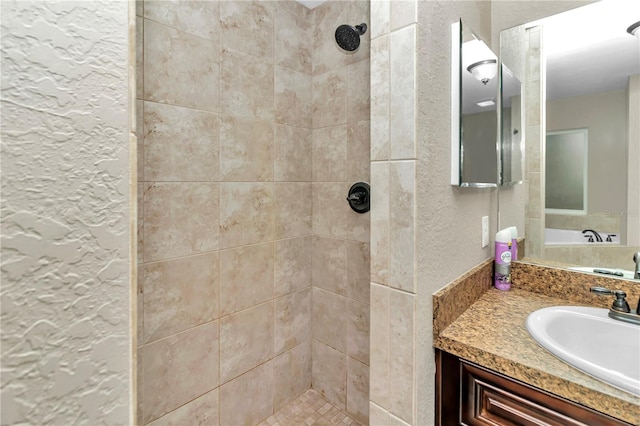 bathroom with a tile shower and vanity