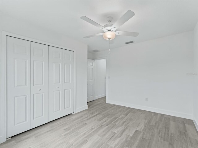 unfurnished bedroom with ceiling fan, light wood-type flooring, and a closet