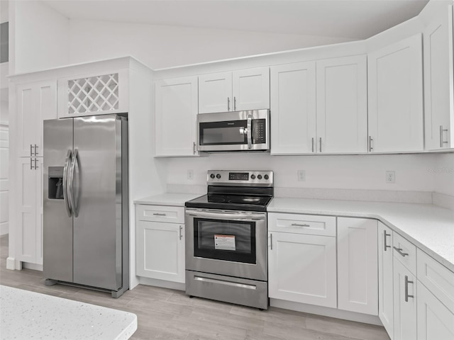 kitchen with white cabinets, vaulted ceiling, and appliances with stainless steel finishes