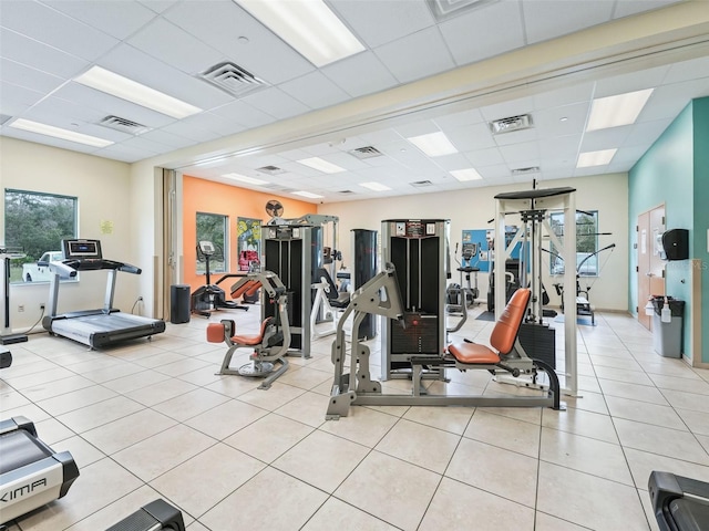 workout area featuring light tile patterned floors and a paneled ceiling