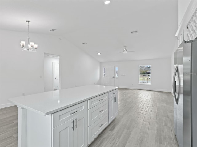 kitchen with stainless steel fridge, ceiling fan with notable chandelier, decorative light fixtures, light hardwood / wood-style flooring, and white cabinets